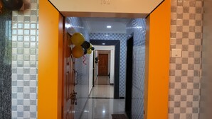 A hallway with checkered floor tiles, a door with a number plate, and a wall with a checkered pattern. - Hotel Nakshtra, Shrungartali (Guhagar)