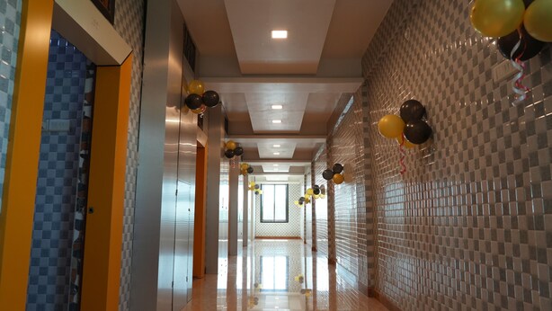 A hallway with checkered walls, a tiled floor, and balloons. - Hotel Nakshtra, Shrungartali (Guhagar)