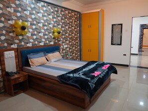 Un dormitorio con pared estampada, una cama con cabecera azul, una mesita de noche de madera y un armario.