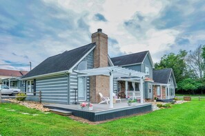 Een huis met twee verdiepingen, een overdekte veranda, een bakstenen schoorsteen en een verzorgd gazon.