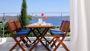 Una terraza con mesa y sillas, vista al mar y una cortina blanca.