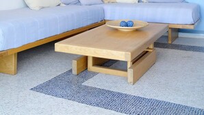 Una sala de estar moderna con un sofá azul claro, una mesa de centro de madera y un pequeño estante de madera con adornos.
