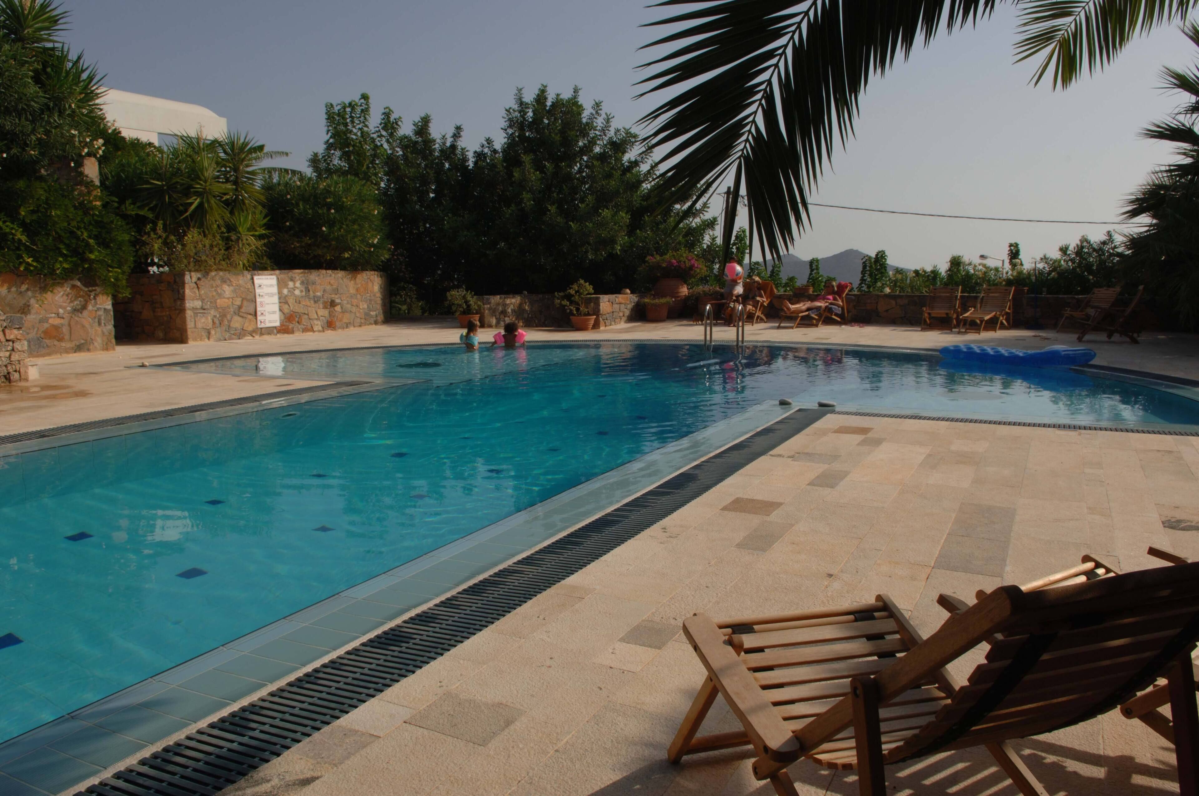 A swimming pool with lounge chairs and a stone wall.