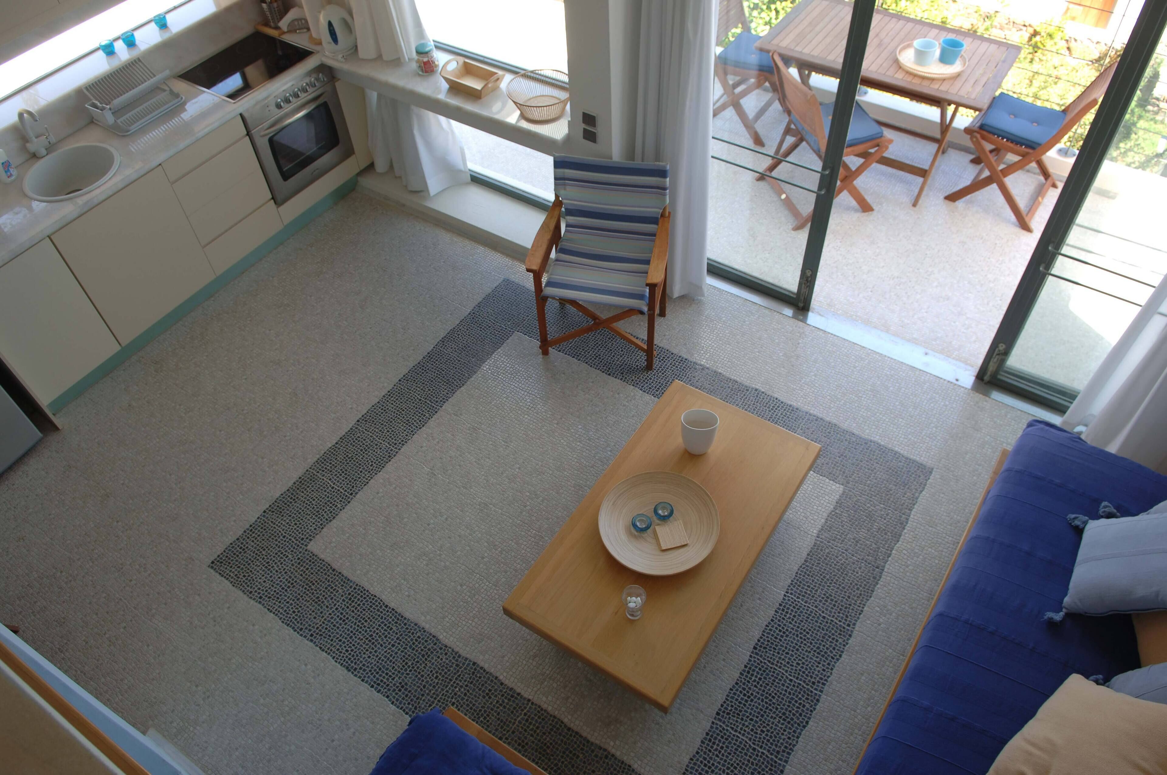 Una cocina moderna con horno y pileta integrados, un comedor con mesa y sillas, y un ventanal que ofrece vistas al exterior.