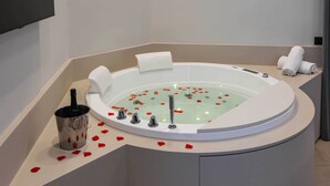 A modern bathroom with a freestanding bathtub, a handheld showerhead, and a bottle of champagne. - Dimora Angioina  (Naples)