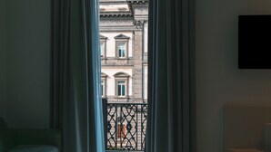 A room with a view of a building through a window with curtains. - Dimora Angioina  (Naples)
