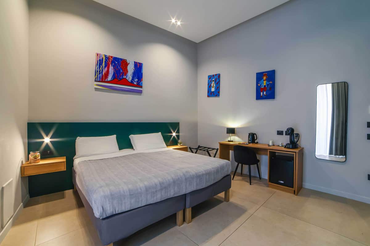 A modern bedroom with a bed, bedside tables, a desk, and a chair.