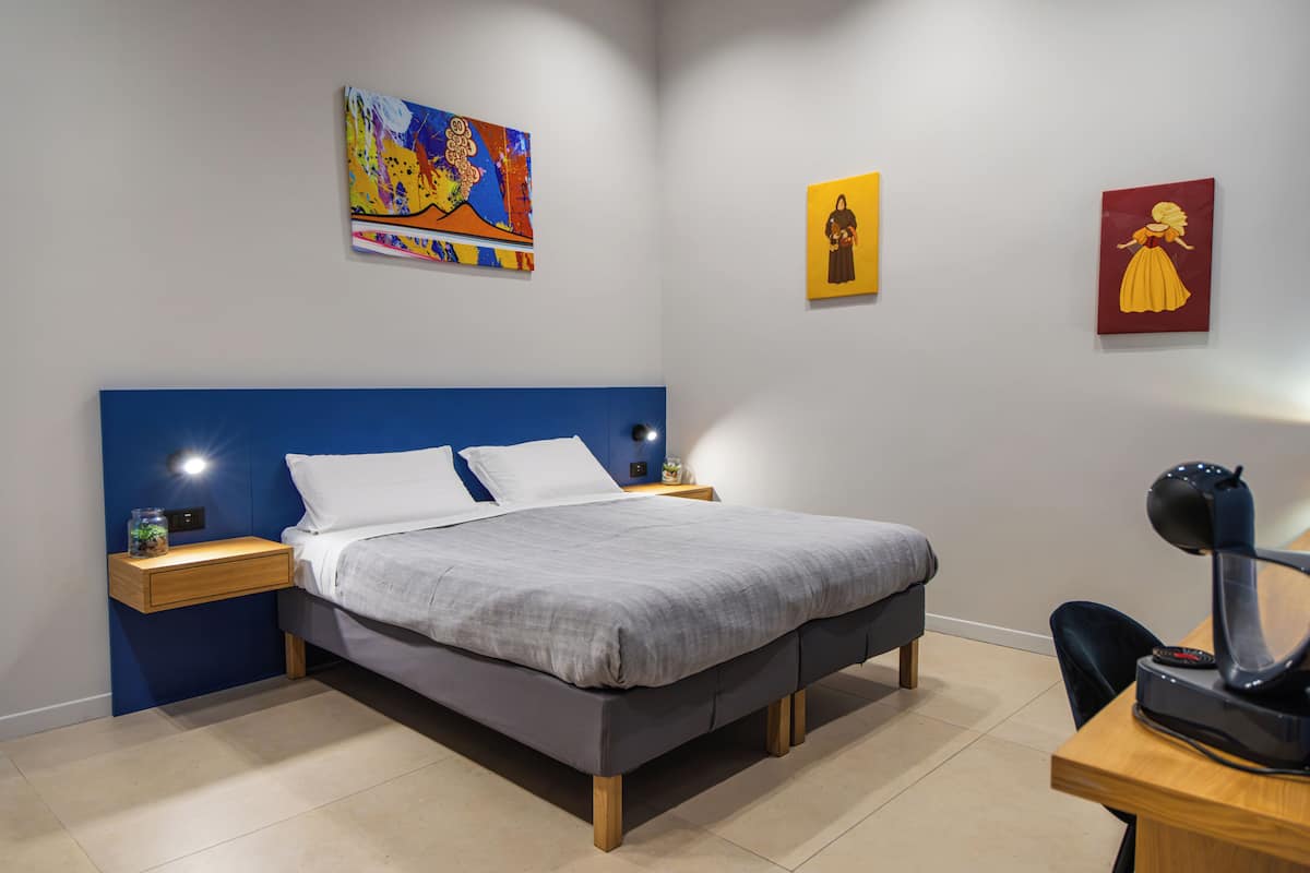 A modern bedroom with a bed, bedside tables, and artwork on the walls.