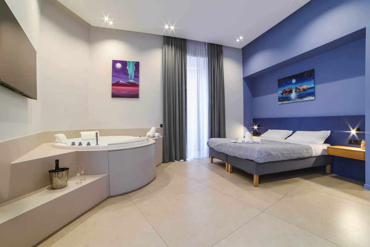 A modern bedroom with a bed, a built-in bathtub, and artwork on the walls.