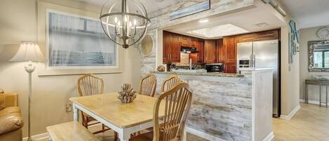 A modern kitchen with a marble island, wooden cabinets, and stainless steel appliances.