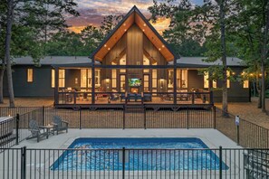 A cabin with a deck, pool, and a large TV screen.