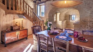 A rustic dining area with a wooden table, chairs, and a staircase with wooden railings. - Promo Dernière Minute Magnifique (Beynac-et-Cazenac)