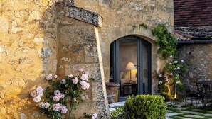 A stone building with a window, a door, and potted plants. - Promo Dernière Minute Magnifique (Beynac-et-Cazenac)