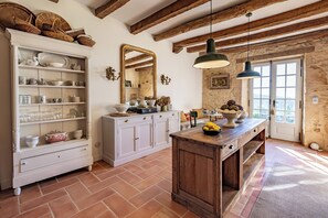 Une cuisine avec des meubles blancs, un îlot central en bois et un grand miroir.
