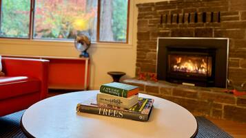Un salon avec une cheminée, un canapé rouge et une table avec des livres.