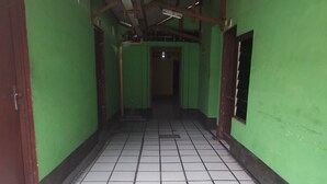 A narrow hallway with green walls and white tiled flooring. - Hotel O Penginapan Keluarga (Medan)