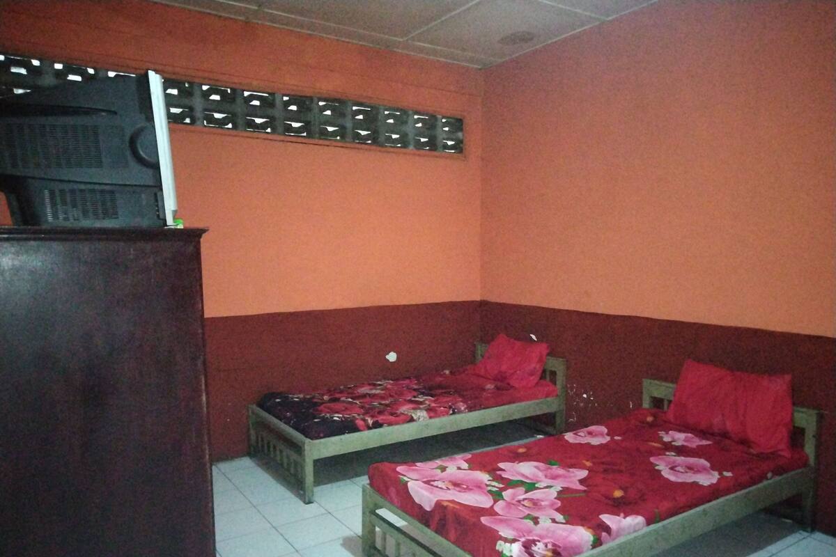 A room with two single beds, each with a floral bedspread and red pillows.