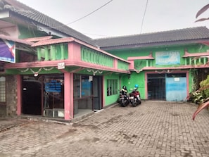 A building with a green facade and a tiled roof. There are two motorcycles parked in front.