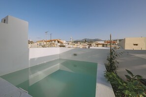 A rooftop terrace with a pool, white walls, and a view of surrounding buildings. - Minoos Residence, Central restored/modern 3floor house w/ seasonal roof pool (Rethymno)