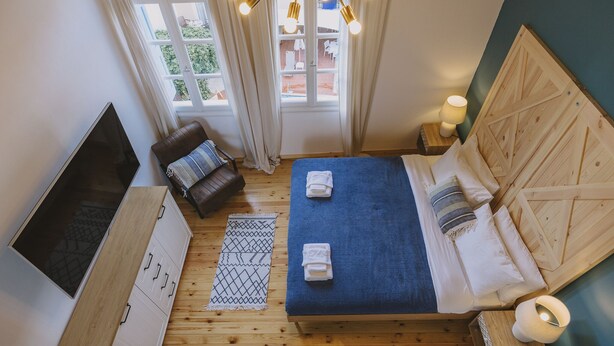 A bedroom with a bed, a TV, a wooden cabinet, and a window with curtains.