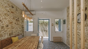 A dining area with a wooden table and chairs, stone walls, and a patterned floor.