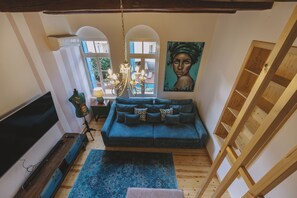 A cozy living room with a blue sofa, a TV, and a painting on the wall. - Minoos Residence, Central restored/modern 3floor house (Rethymno)