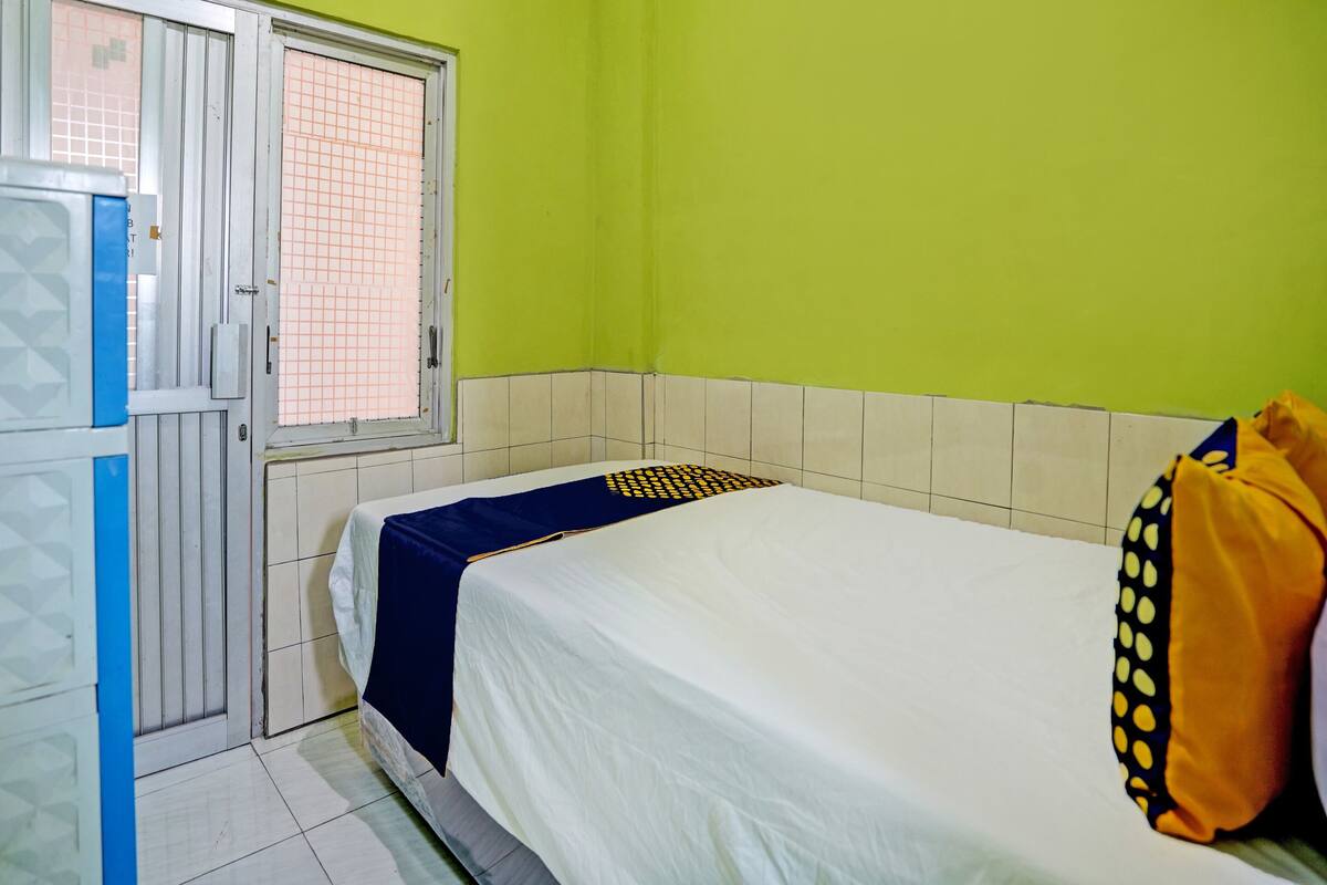 Ein Zimmer mit einem Bett, einem Fenster mit Gittermuster und einer Tür mit blau-weißem Dekor.