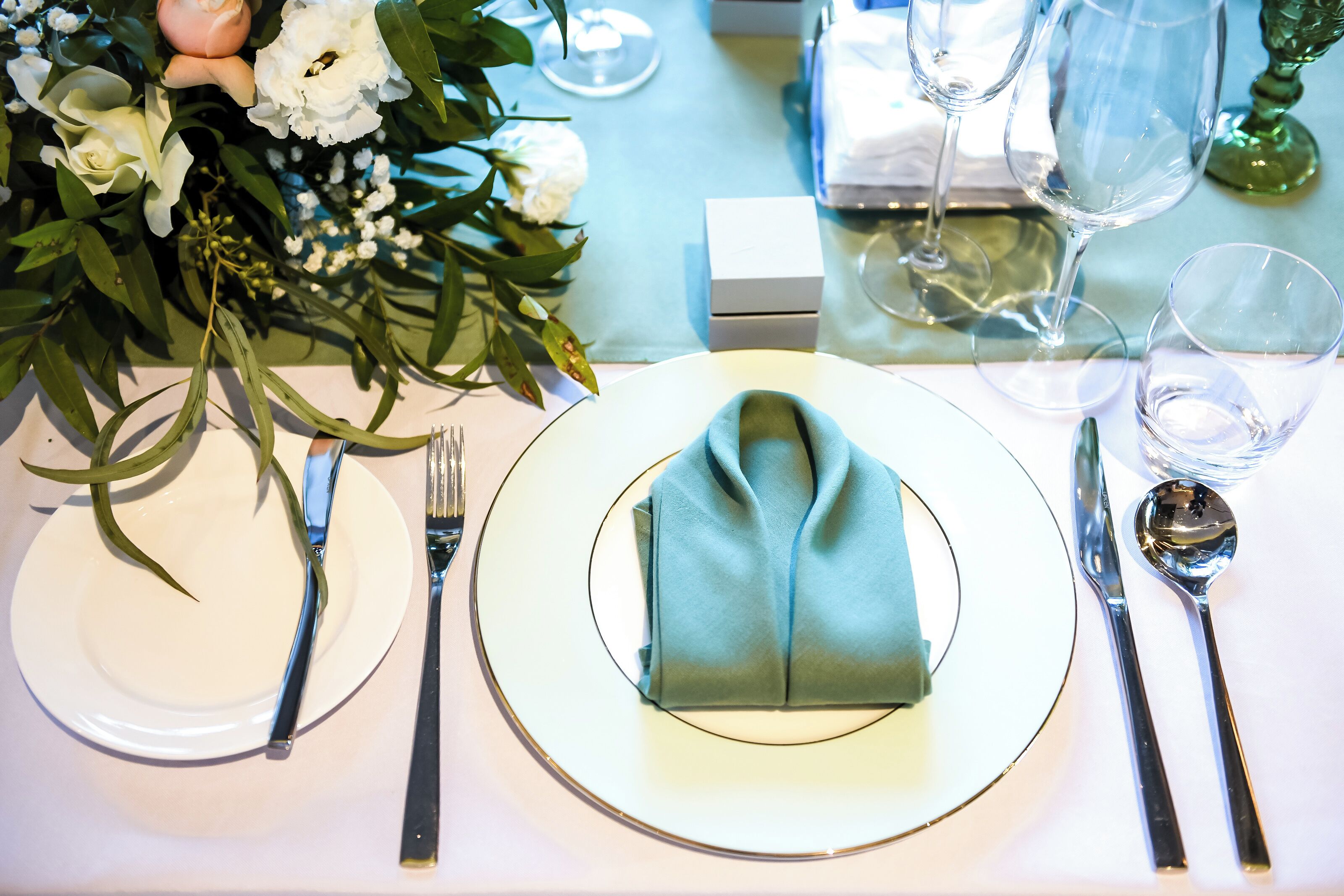 A table set with white plates, silver cutlery, and a folded napkin.