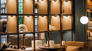 Un intérieur moderne comprenant un coin salon, une bibliothèque et un mur décoratif agrémenté de luminaires.