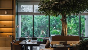 Un restaurant avec un grand arbre au centre, entouré de tables et de chaises.