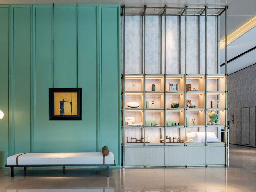 Un interior moderno con una pared color turquesa, un banco y una exhibición de objetos decorativos.