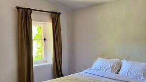 Un dormitorio con cama, cortinas, una ventana y un ventilador de techo.