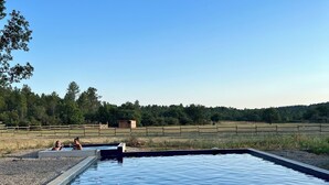 Una piscina rectangular con borde de hormigón, rodeada por una zona de grava.