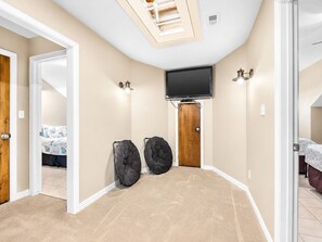 A bedroom with a TV, two bags, a door, and a light fixture.