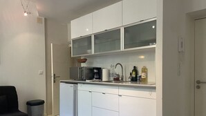 A compact kitchen with white cabinets, a coffee machine, and a sink.