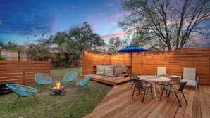 An outdoor patio with a fire pit, seating, and a barbecue area. - Mid Century Charmer, oversize fenced corner yard, fire pit,hot tub, pet friendly (Fredericksburg)