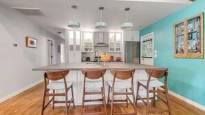 A modern kitchen with a central island, bar stools, and pendant lighting. - Mid Century Charmer, oversize fenced corner yard, fire pit,hot tub, pet friendly (Fredericksburg)