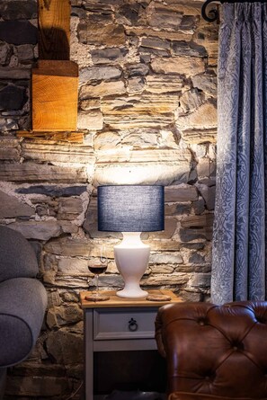 A comfortable retreat with a leather chair, nightstand, and patterned curtain.