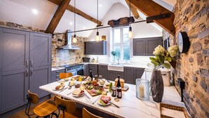 A kitchen with a large island, stone walls, and wooden beams. - The Mill @ Atlow Mill (Atlow)