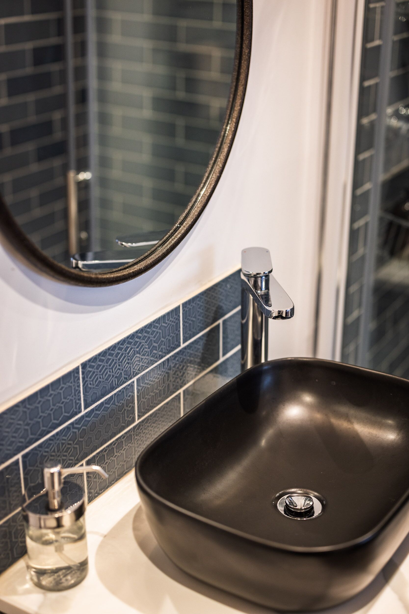 A bathroom sink with a black basin, a chrome faucet, and a mirror above it.