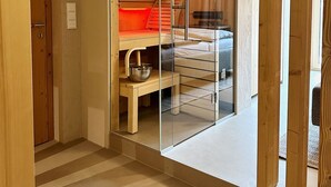 Un dormitorio moderno con separador de vidrio, suelo de madera y un banco empotrado.