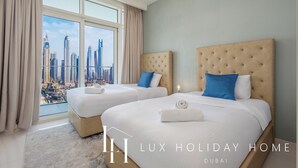 Quarto de hotel com duas camas, um candelabro e vista para a cidade.