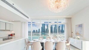 Uma sala de jantar moderna com vista para a cidade, mobiliário branco e um candelabro.