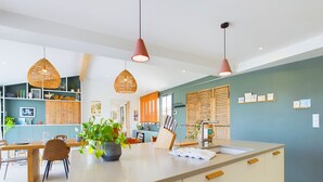 Et moderne køkken med en central ø, hængende lamper og udsigt til spiseområdet.