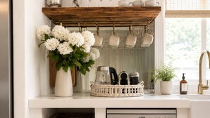 Una cocina con lavavajillas Bosch, cestas de mimbre, un jarrón con flores y una estantería de madera con utensilios de cocina.