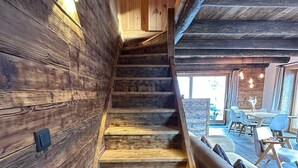 A wooden staircase leading to a dining area with modern furniture.