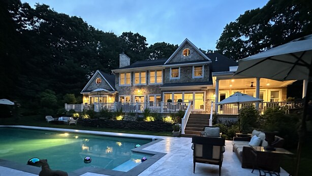 Une grande maison avec une piscine, un espace extérieur aménagé pour s’asseoir et une terrasse couverte.