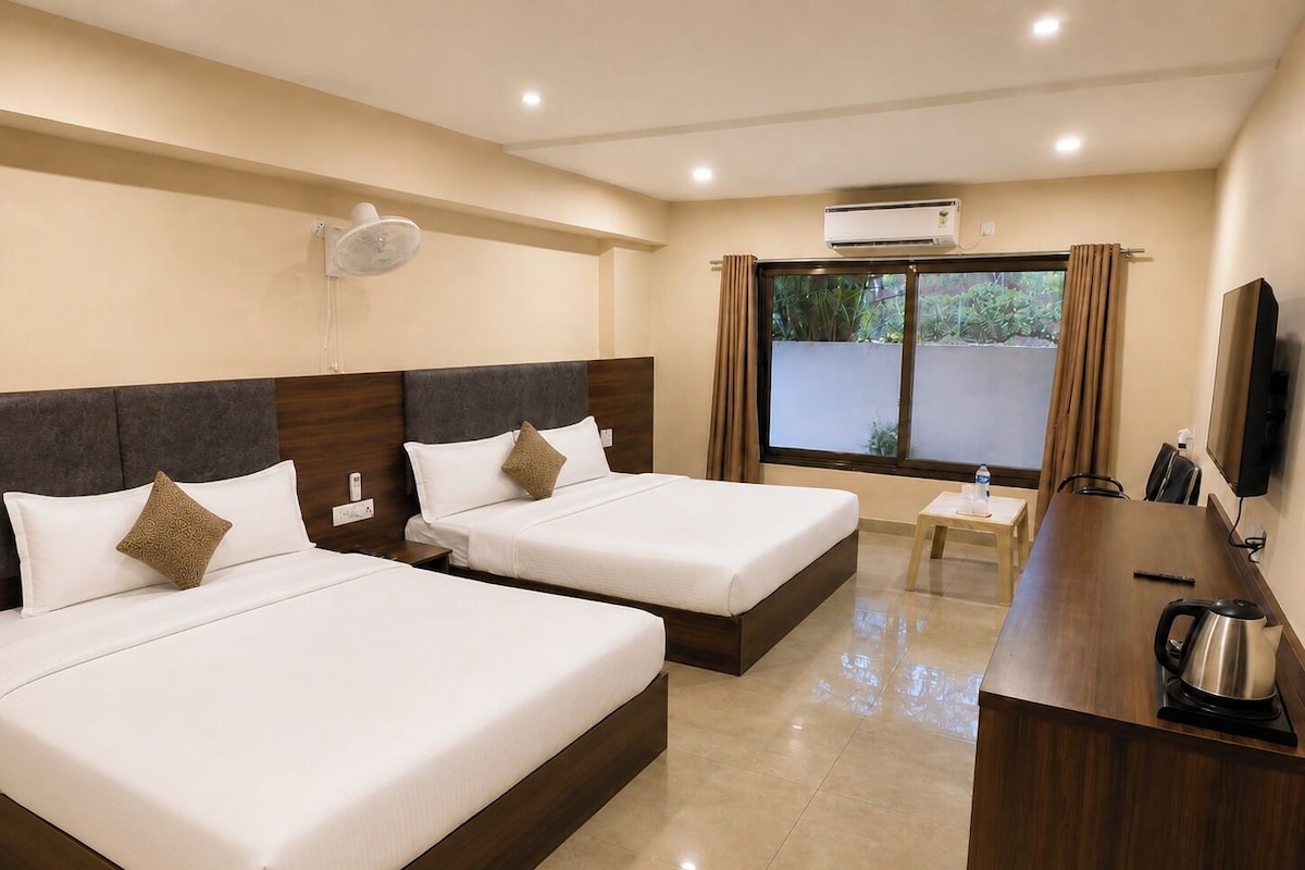 Una habitación de hotel con dos camas, un escritorio con hervidor, televisión y aire acondicionado.