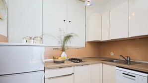 A modern kitchen with white cabinets, a built-in dishwasher, and a countertop with a vase of flowers. - Sunset Oasis (Dubrovnik)