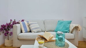 A living room with a sofa, cushions, a coffee table, a book, a glass with a drink, and a potted plant. - Sunset Oasis (Dubrovnik)
